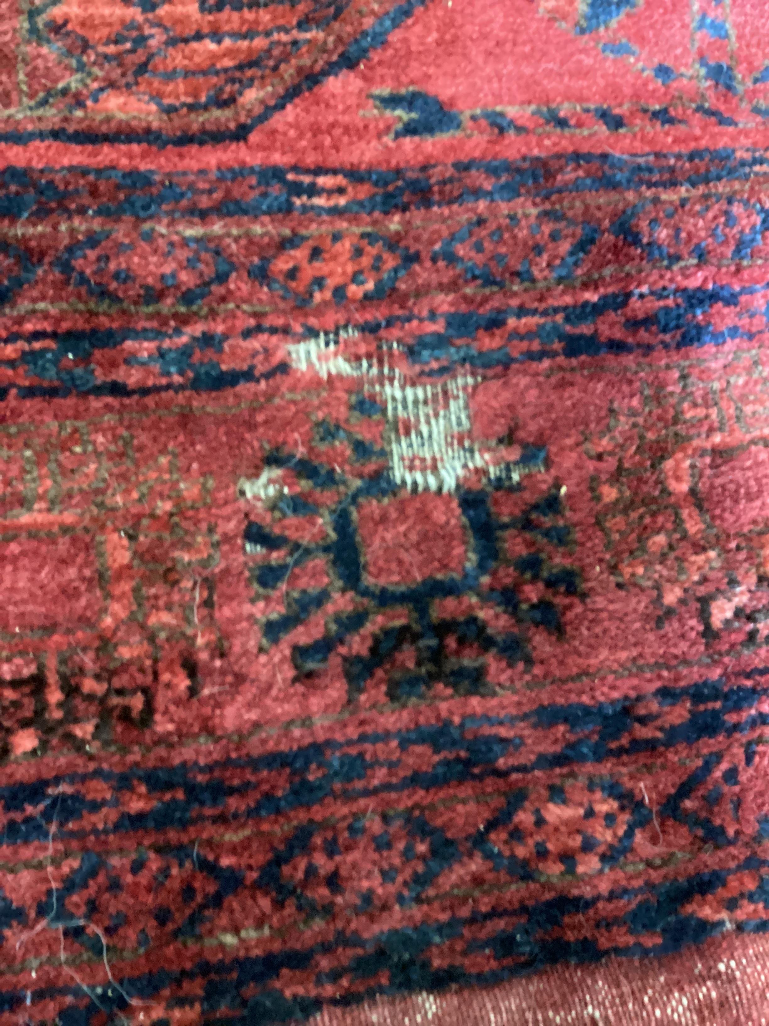 A Bokhara red ground carpet, worn and holed, 286 x 214cm